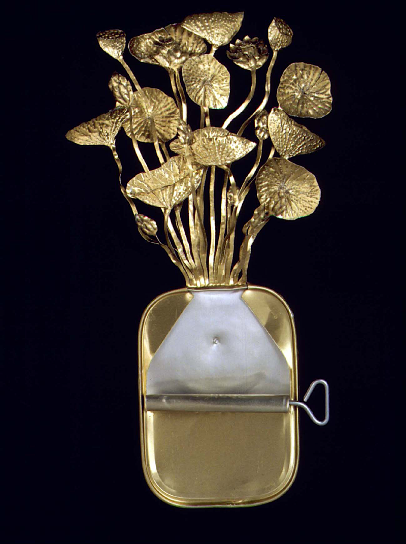 A gold-toned sardine can with cluster of sculptural lotus or water-lily leaves and buds emerging, shown against a very dark background.

Lotus by FionaHall, Artwork copyright Fiona Hall - Image copyright Piper Press.
