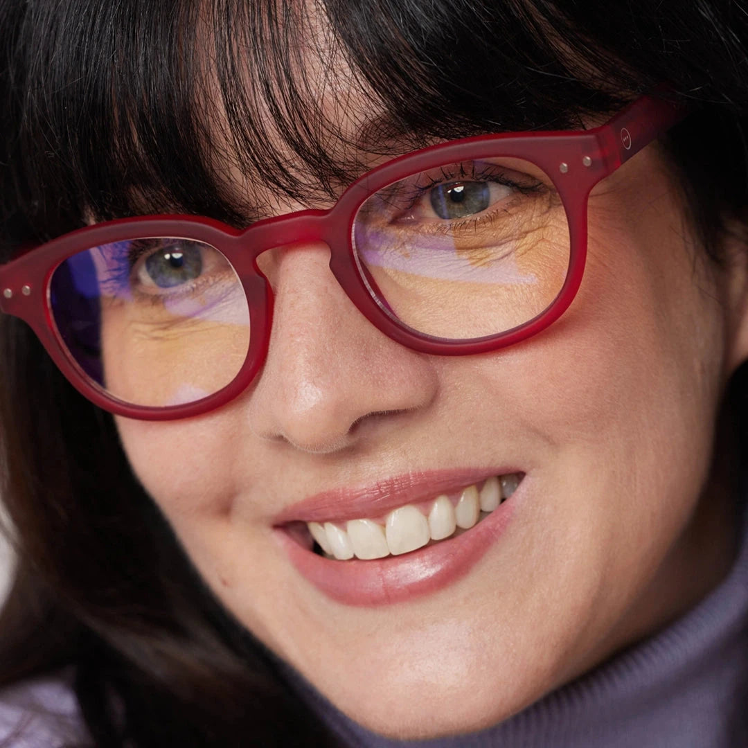 Close-up of a person wearing red glasses with a blurred background